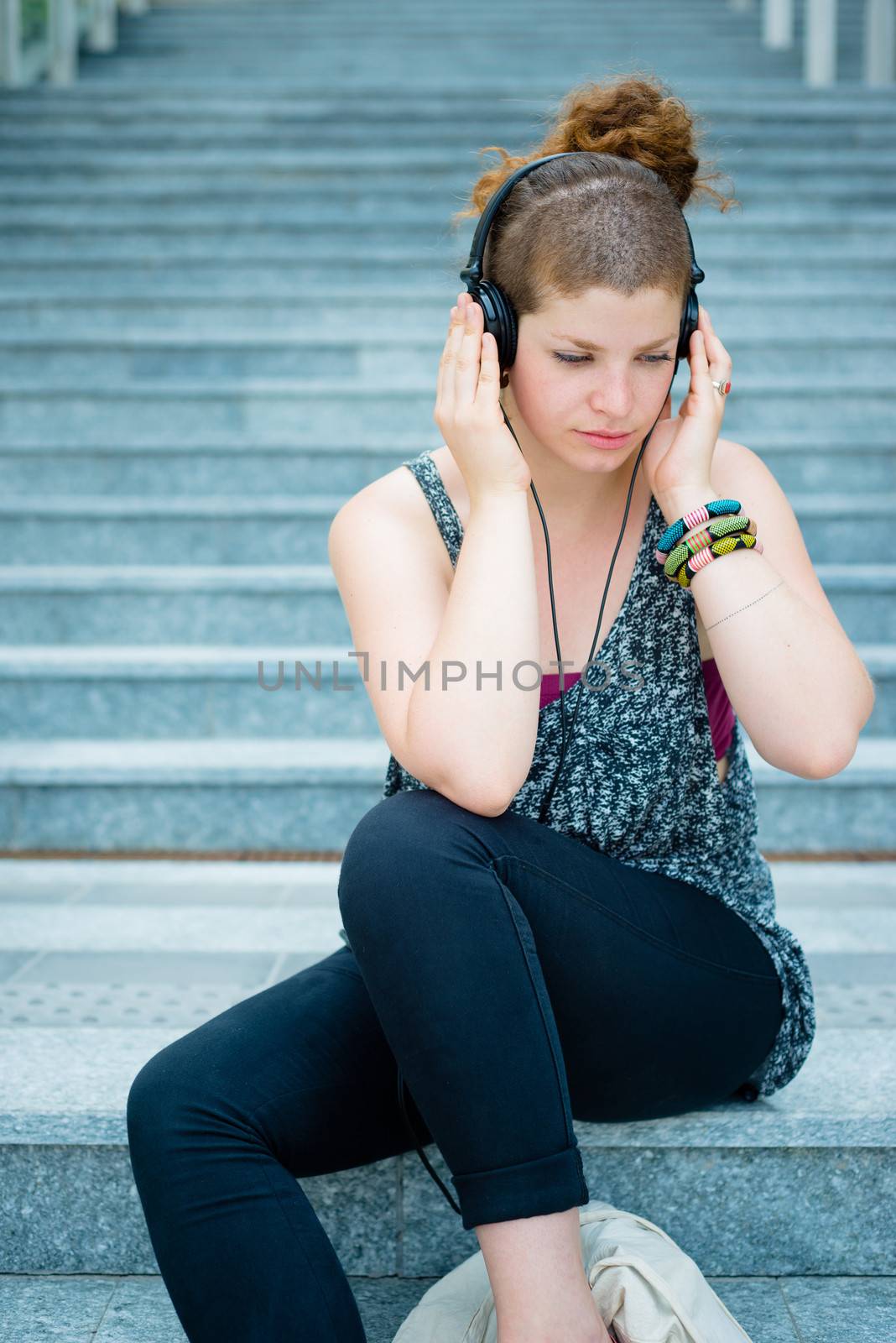 beautiful stylish modern young woman listening to music in the city