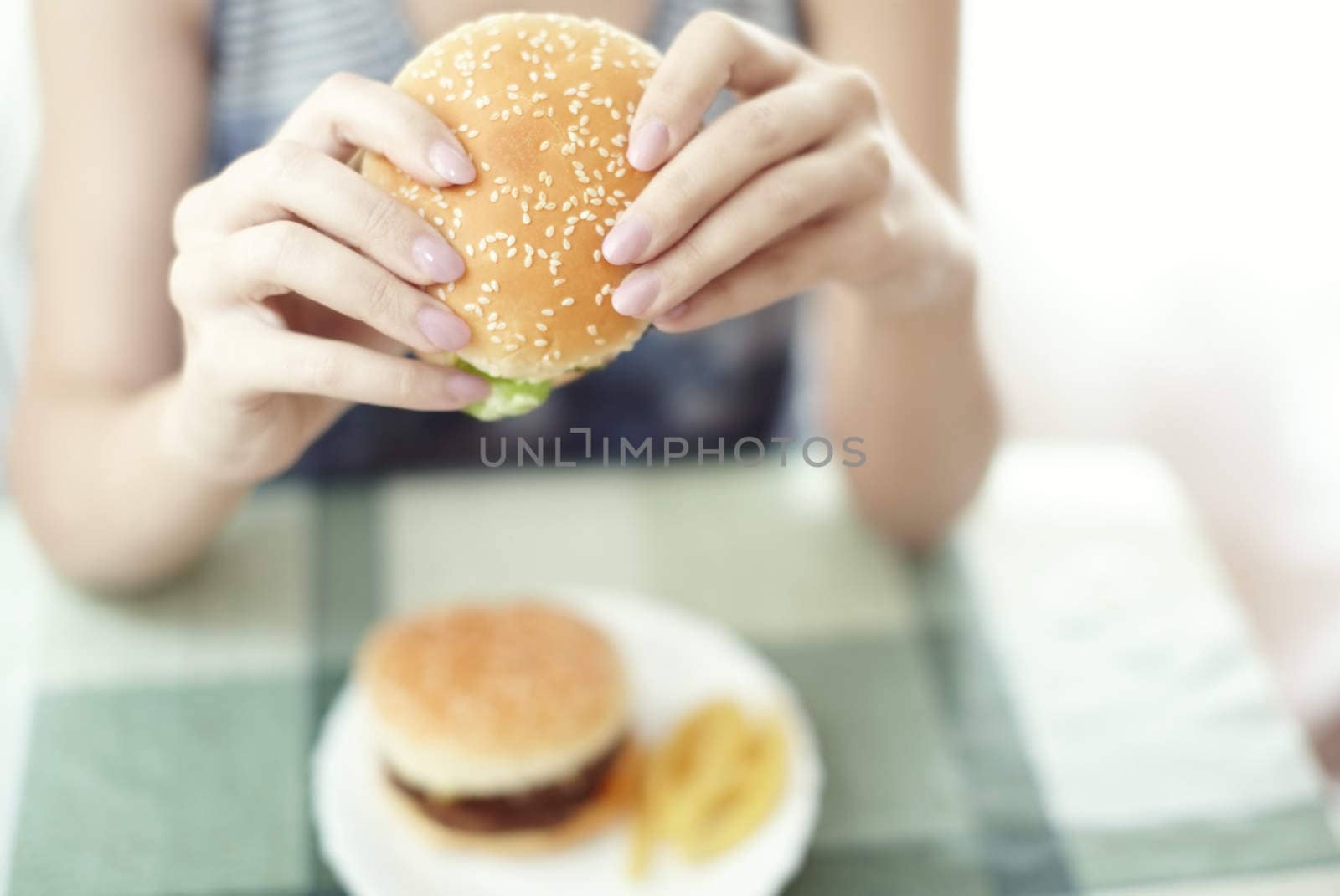 Woman holding humburger and sitting at the table