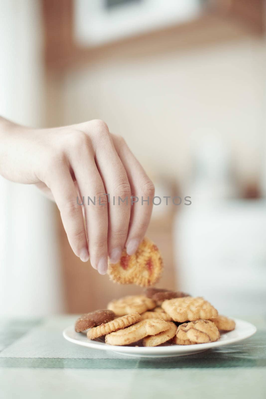 Human hand taking cookie in plate on a table