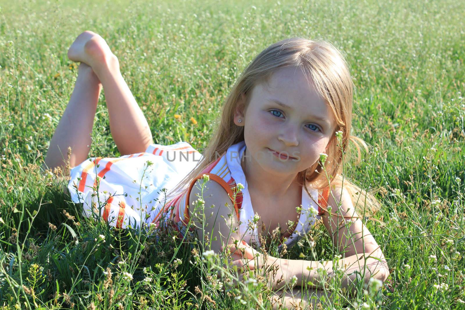 portrait of little girl lying on the grass by alexmak