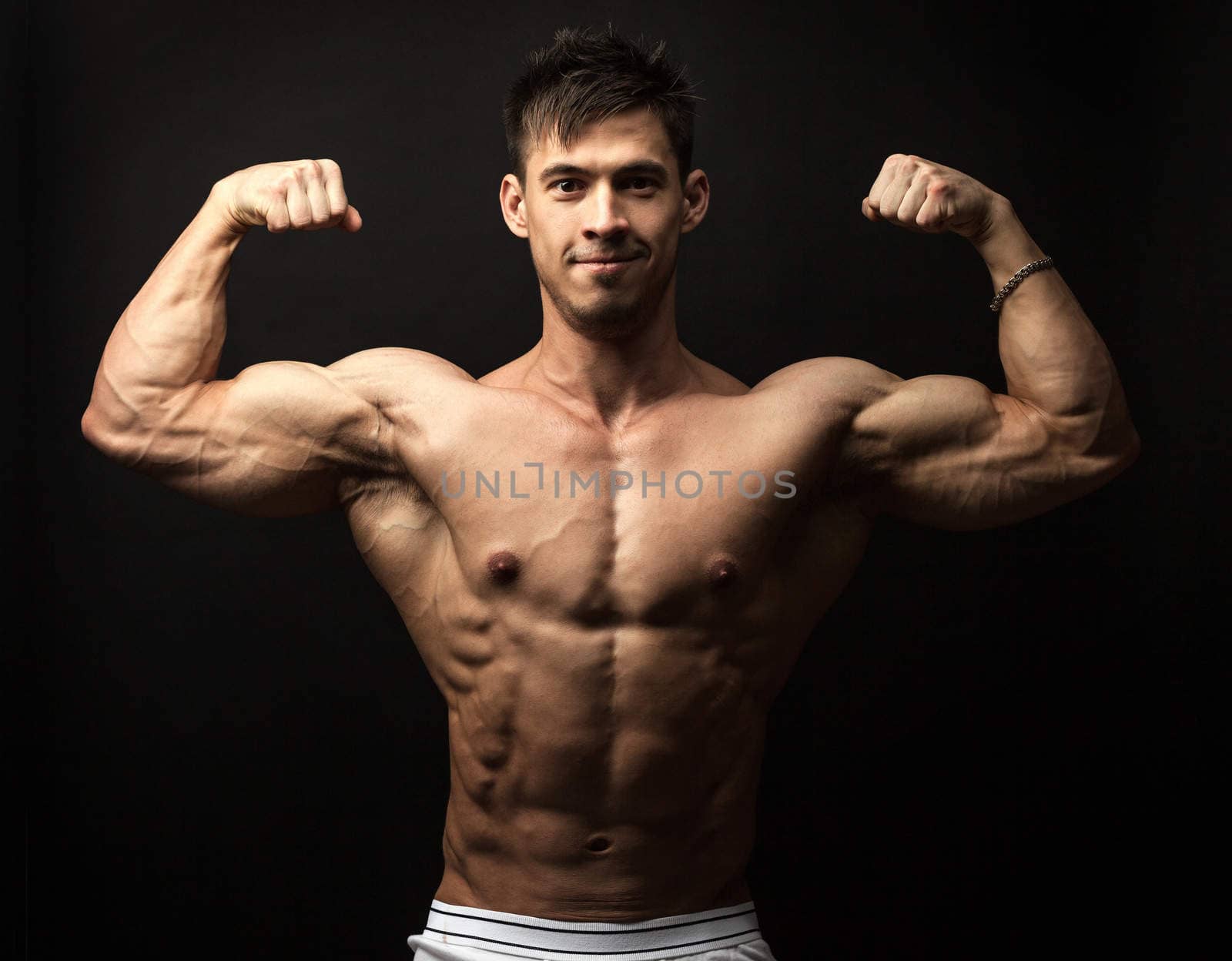 Portrait of muscular man flexing his biceps by photobac