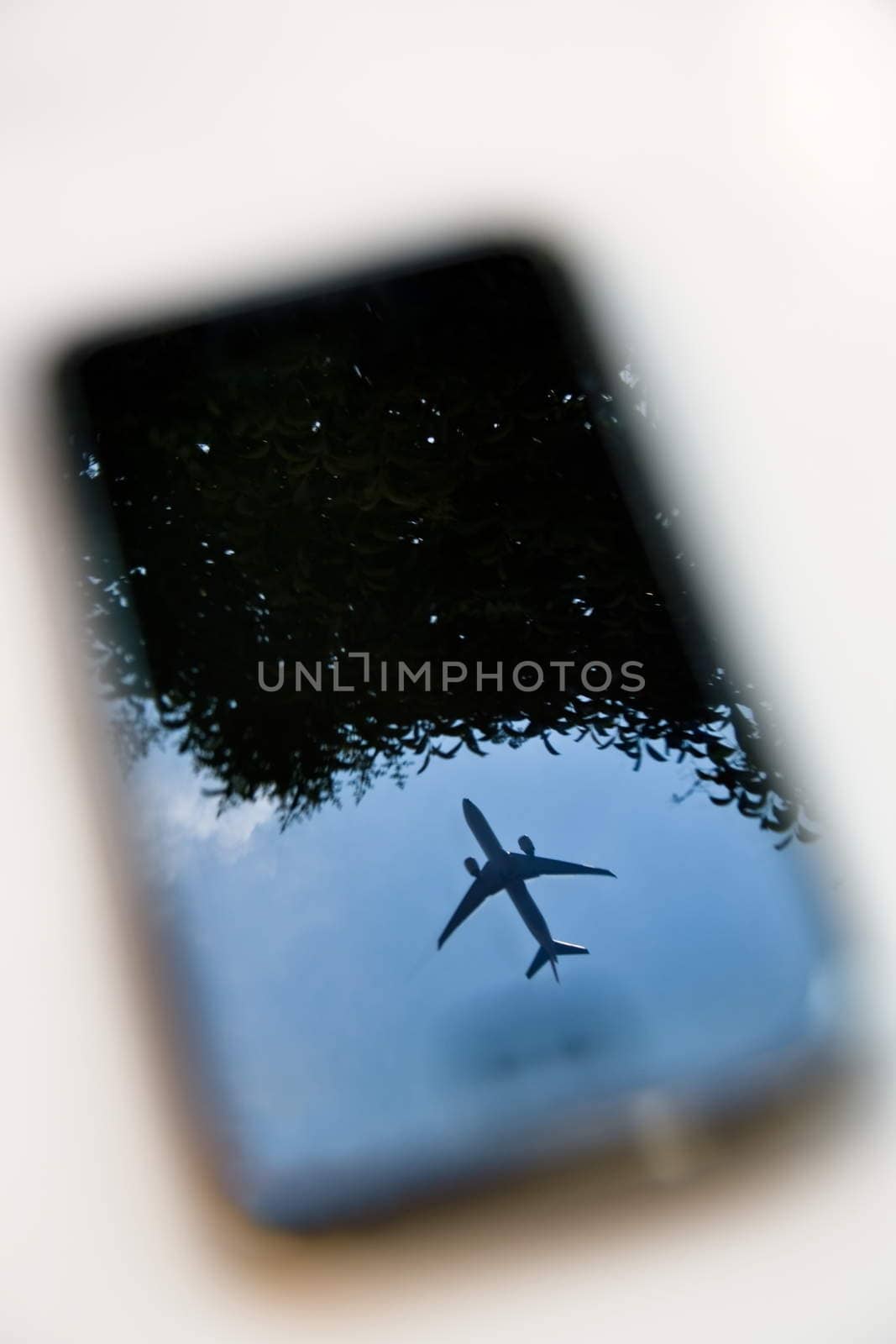 plane reflection on mobile phone with blue sky and tree