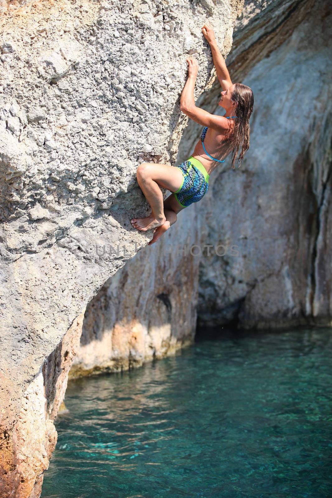 Deep water soloing, young female rock climber on cliff