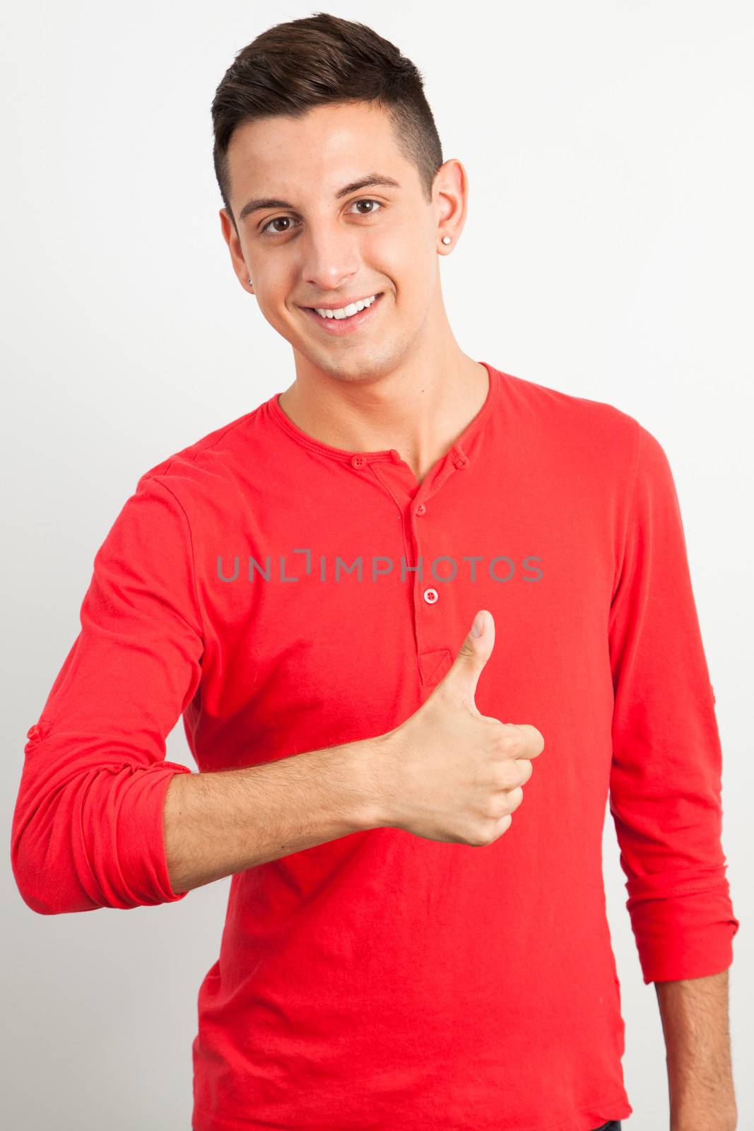 Young man smiling and doing thmb up by Izaphoto