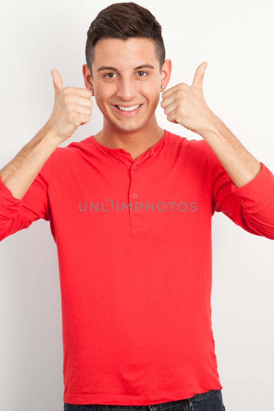 Young man smiling and doing thmb up by Izaphoto