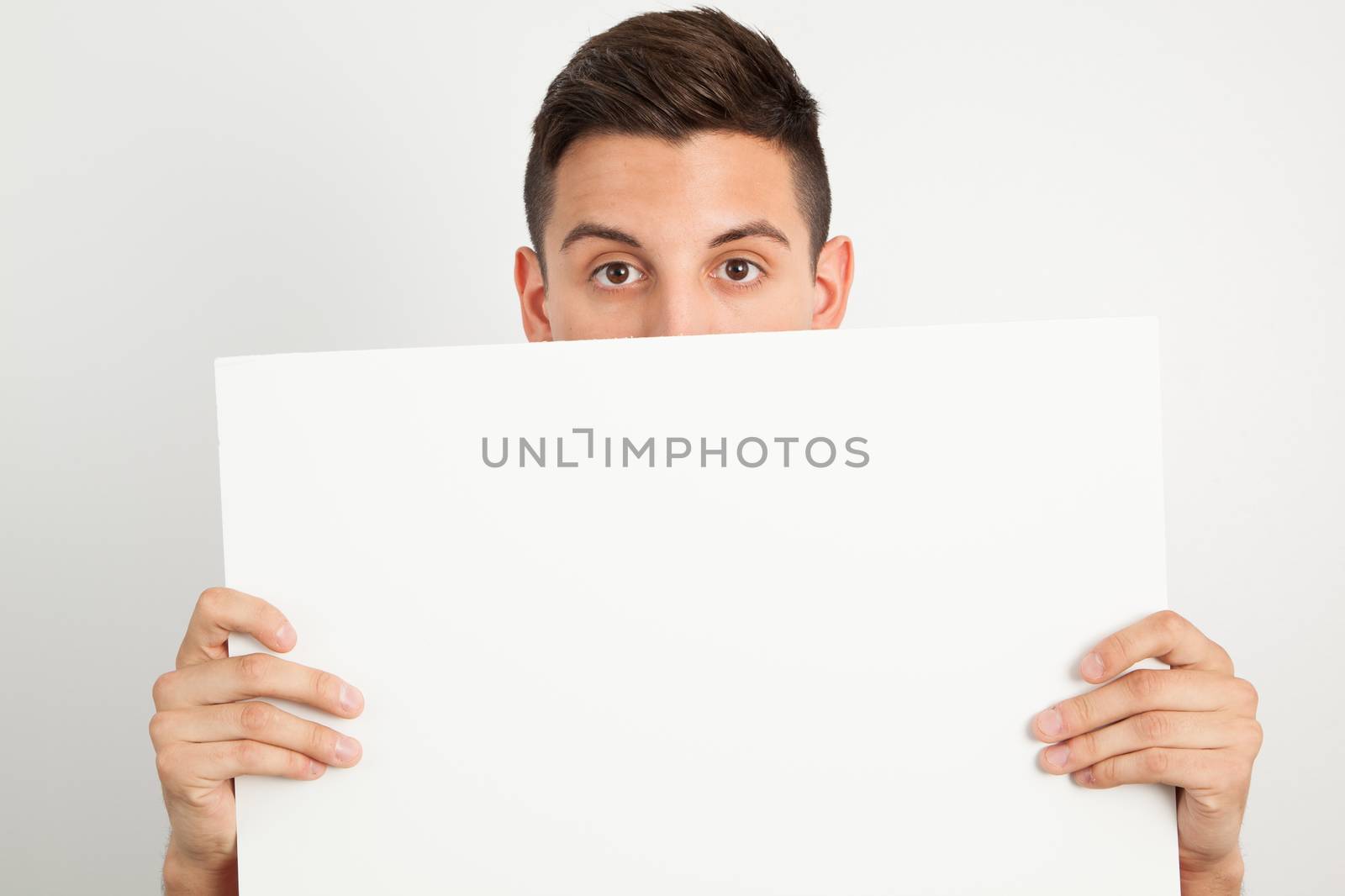 Young man holding a white board by Izaphoto