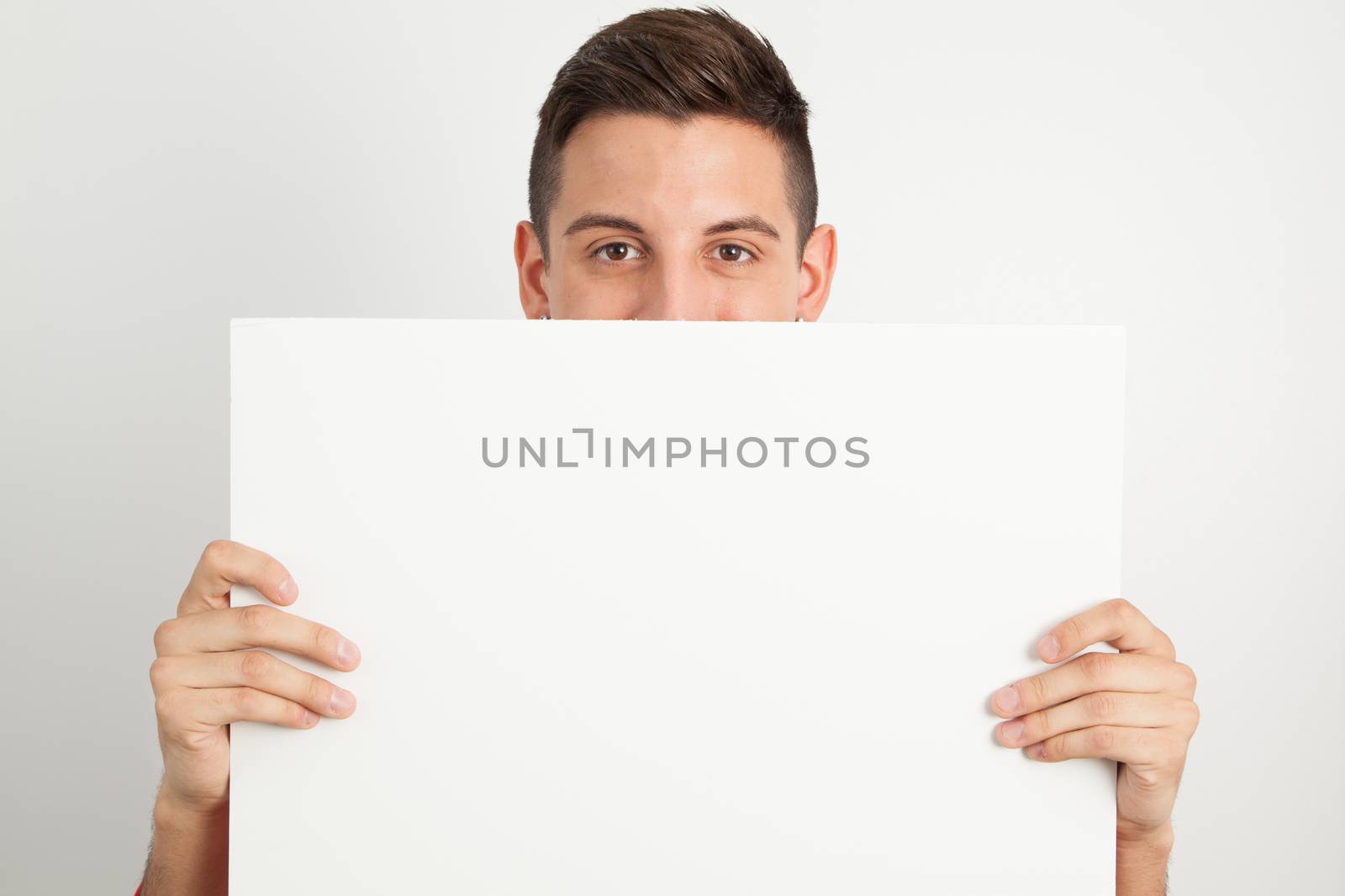 Young man holding a white board by Izaphoto