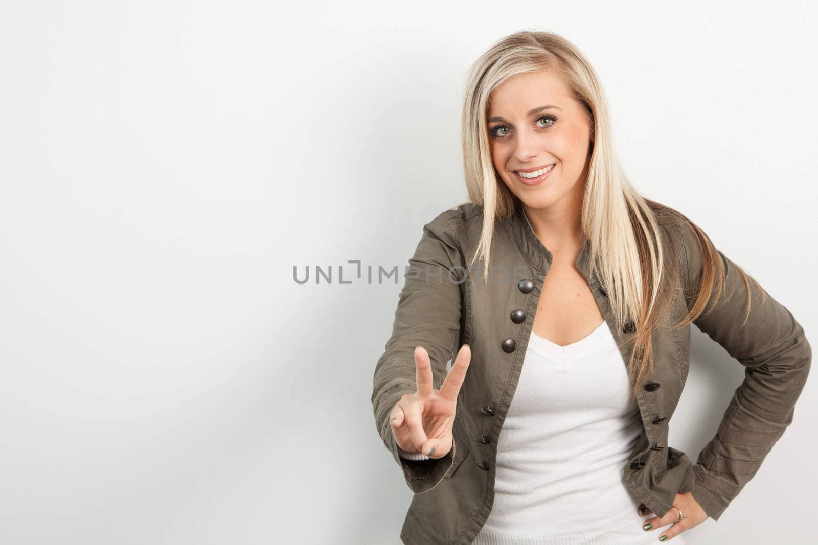 Young blond women smiling and doing a peace sign by Izaphoto