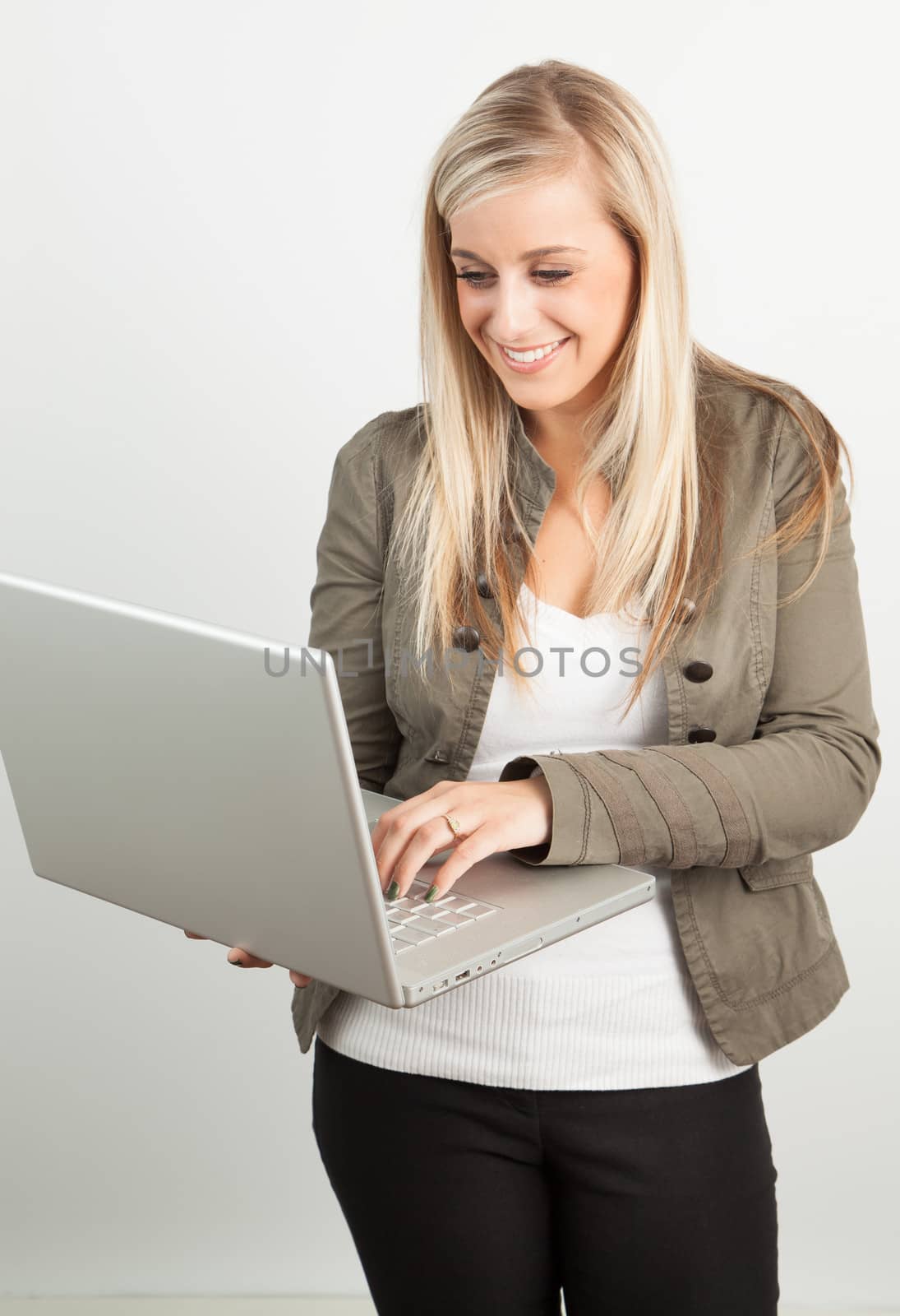 Portrait of a young blond woman smiling wiith a laptop by Izaphoto