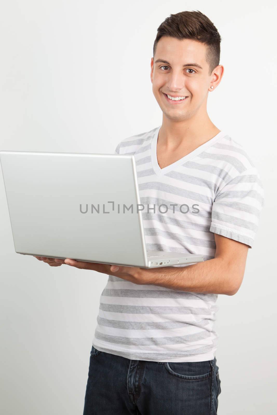 Young man smiling and using a laptop by Izaphoto