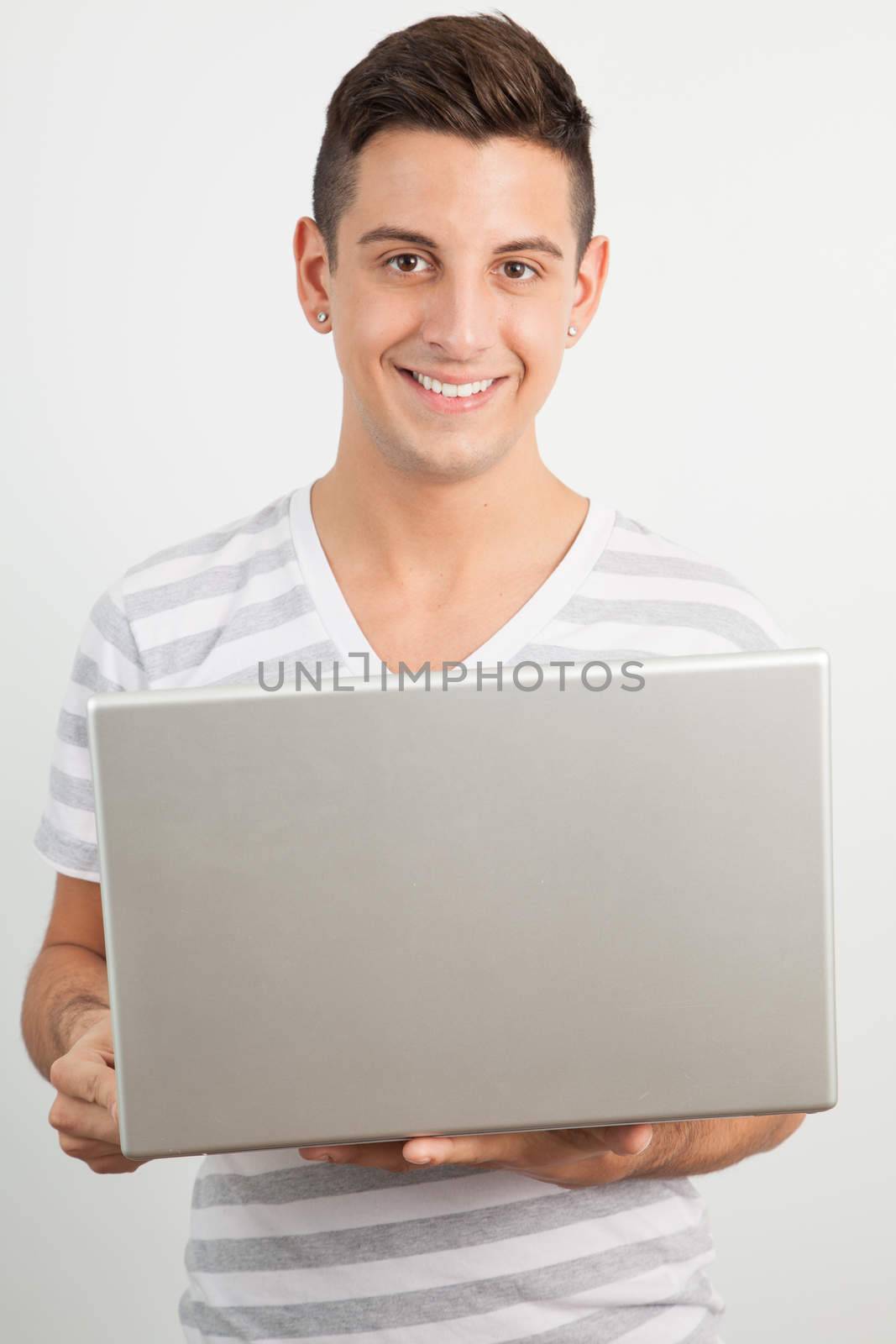 Young man smiling and using a laptop by Izaphoto