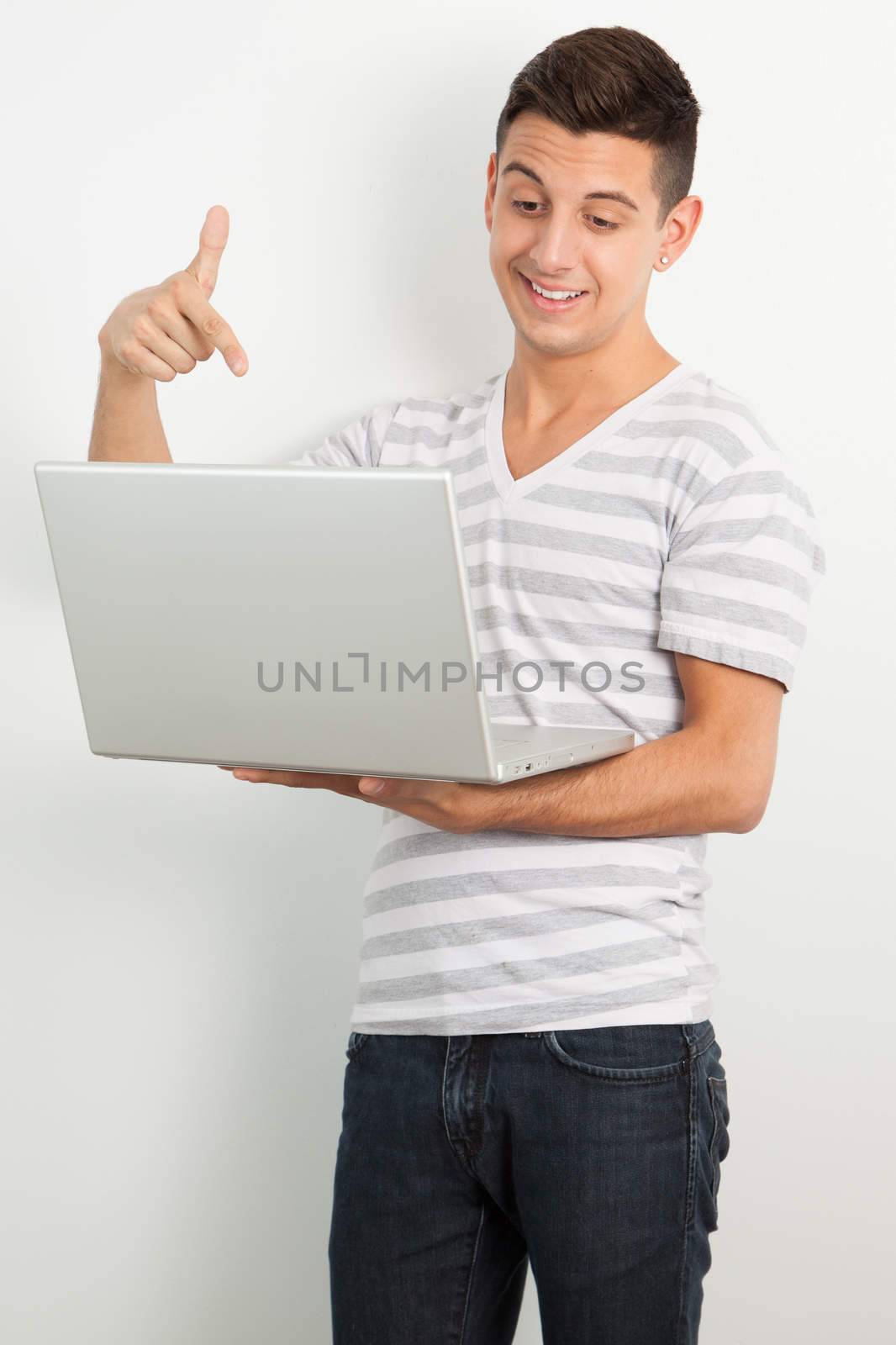 Young man smiling and pointing a laptop by Izaphoto