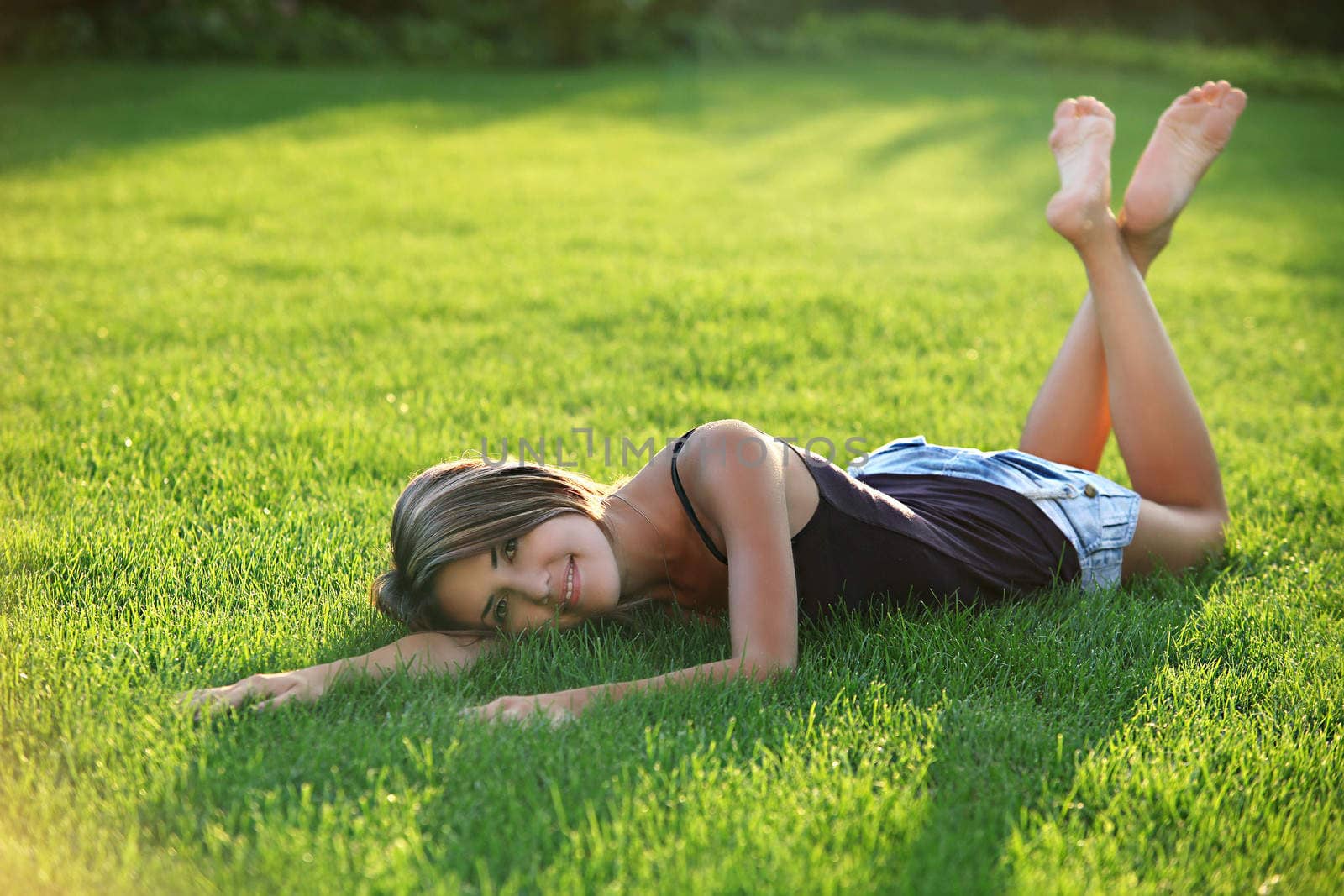 Young woman lying down on grass by photobac