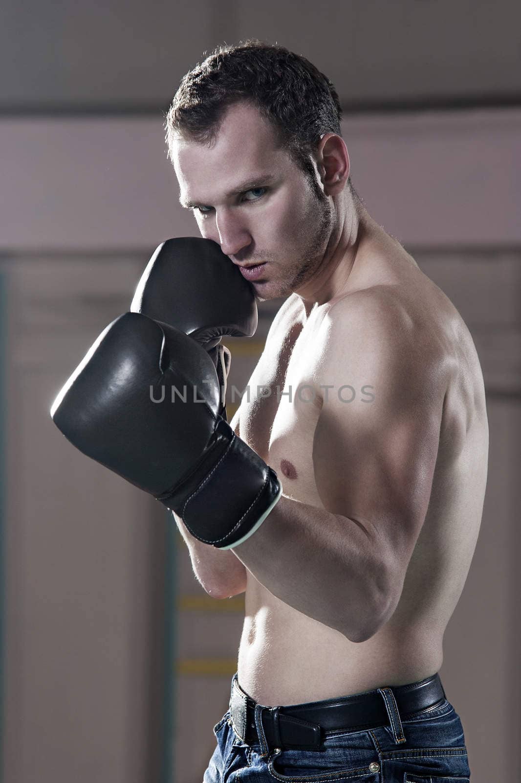 Waist-up of young male boxer in gym