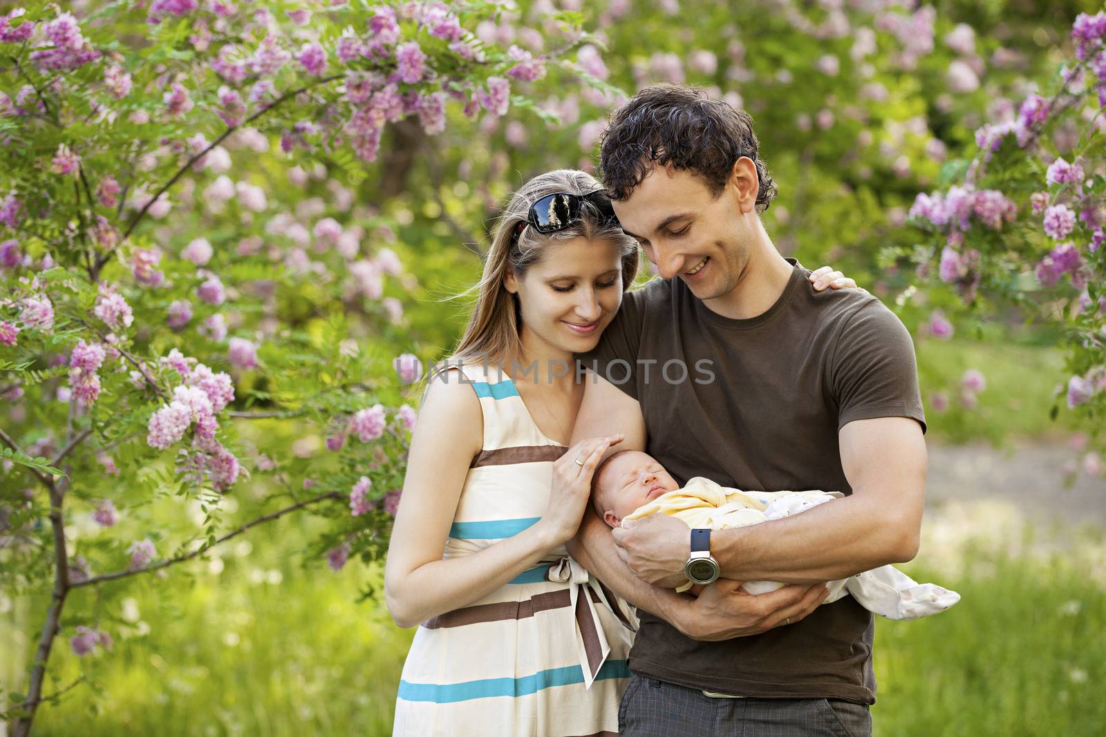 Young couple with newborn son outdoors in spring