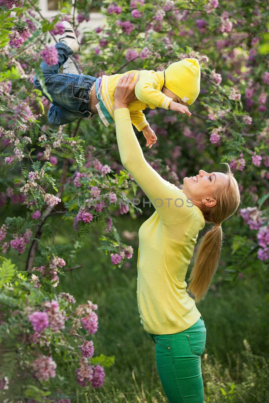 Happy young woman lifting her son high up