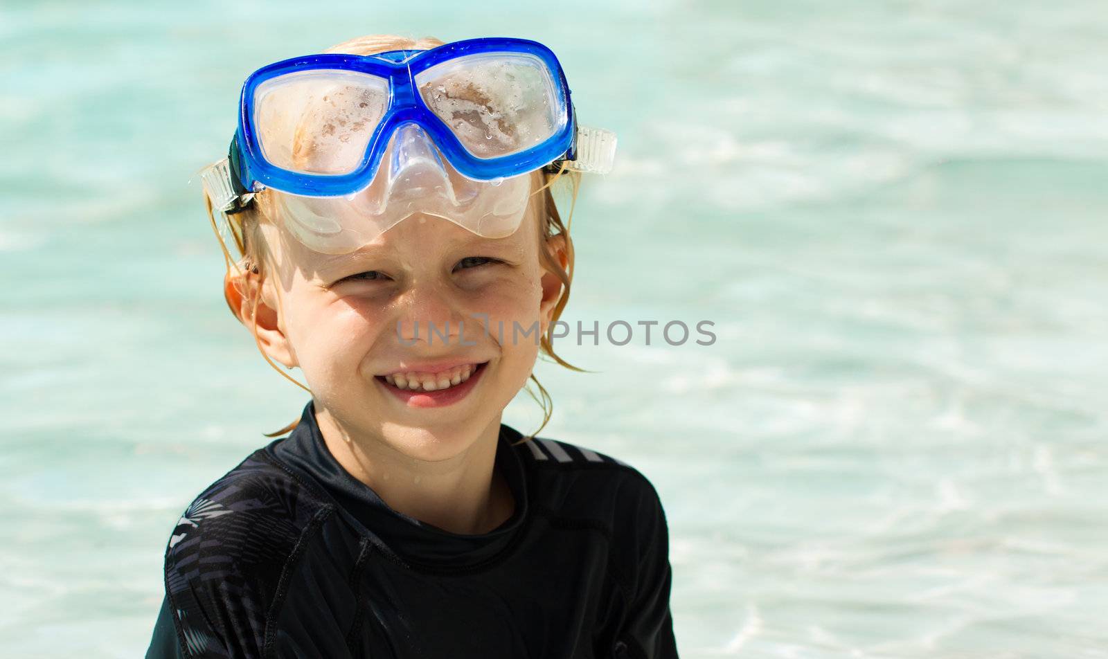 A cute happy young boy in water wearing a dive mask.