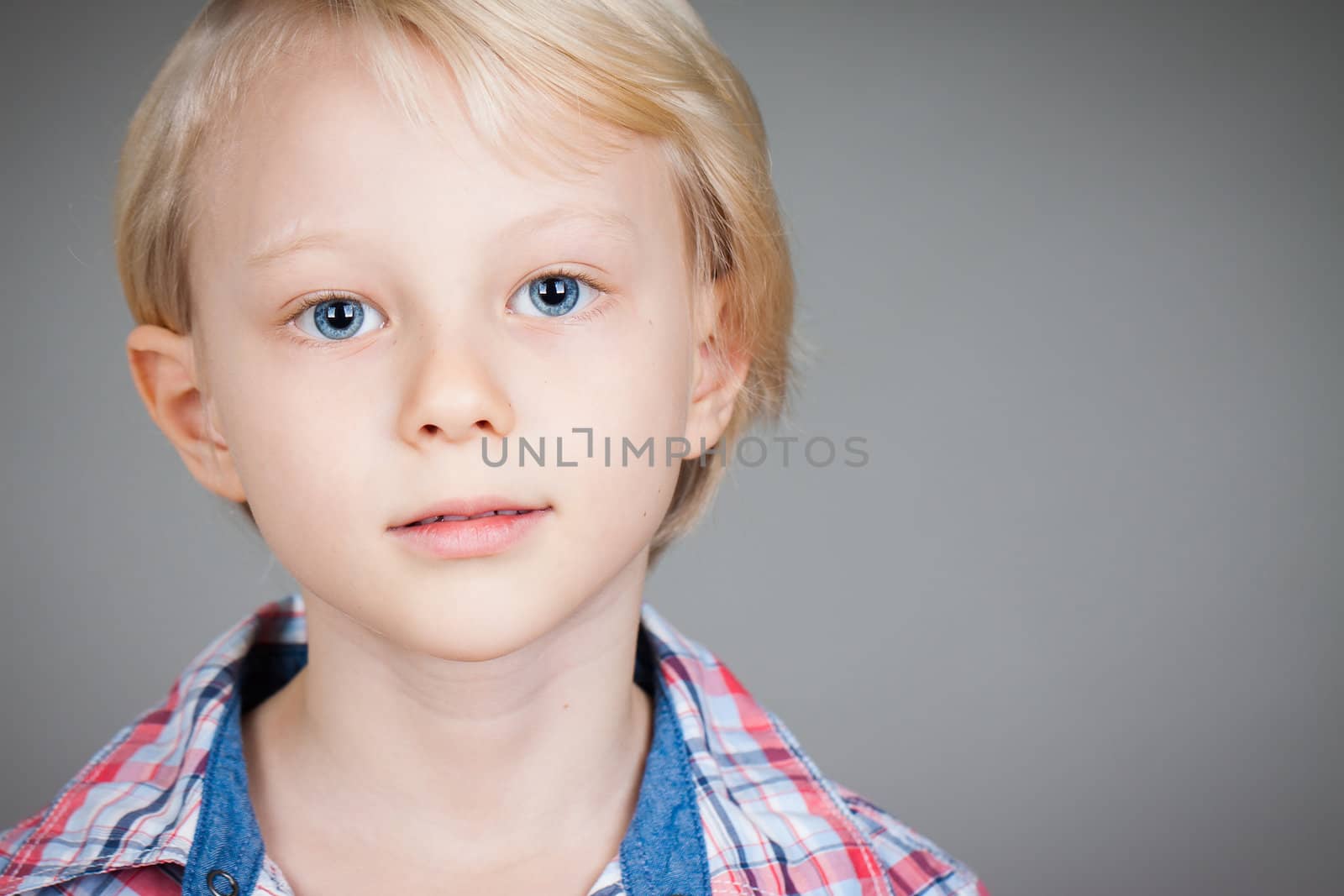A close-up portrait of a serious young boy looking at camera.