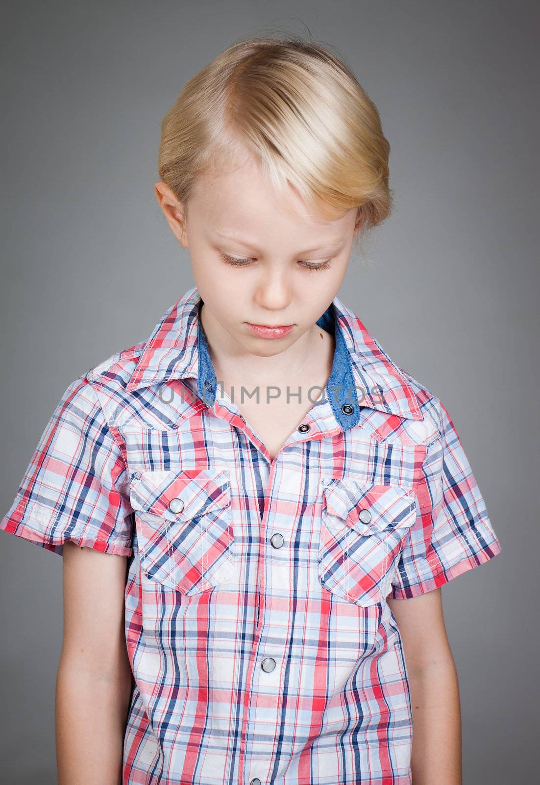 Sad cute thoughtful boy looking down.