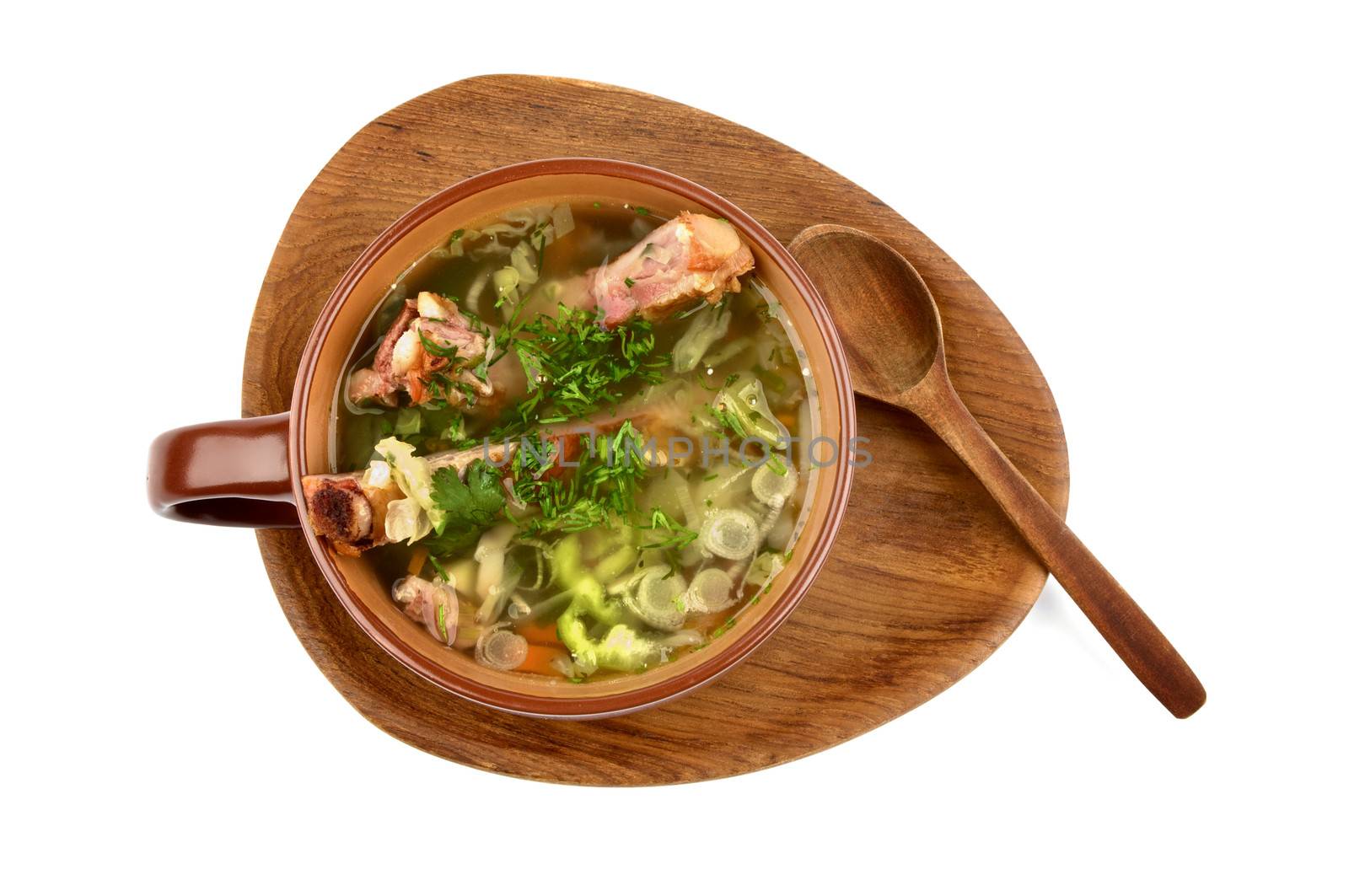 Vegetable Soup with Cabbage, Greens and Smoked Pork Ribs in Brown Bowl with Wooden Spoon on Wooden Plate. Top View