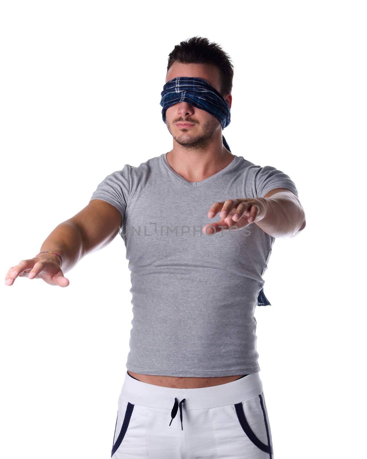 Blindfolded young man feeling his way in the dark, concept of confusion, crisis, problem or challenge