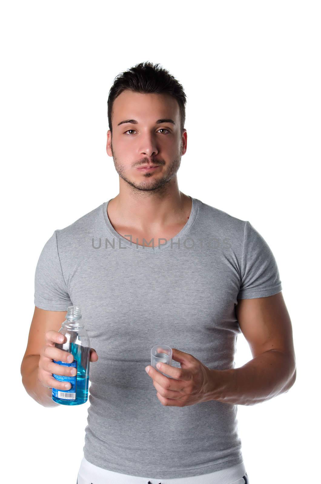 Handsome young man using mouthwash to clean his teeth and mouth, isolated on white background