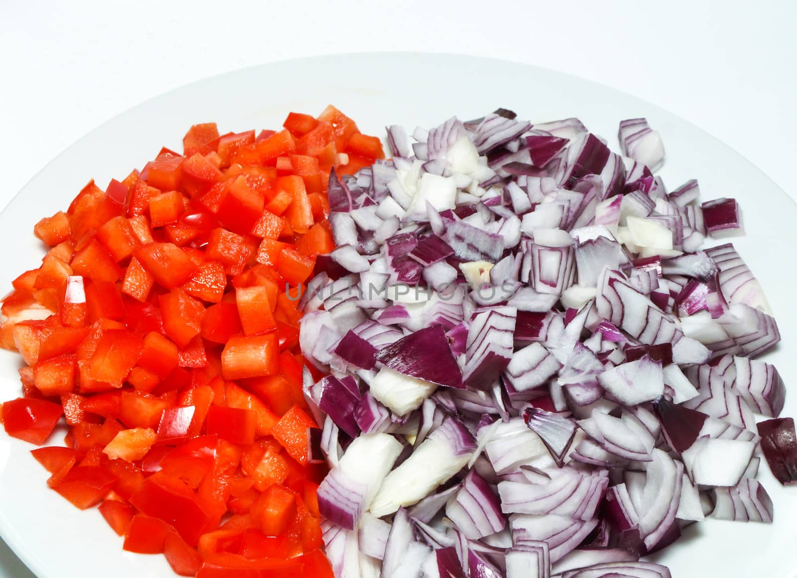 Chopped red onion and red pepper in a white ball, towards white background