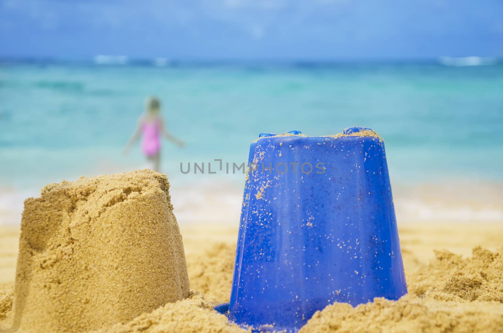 Sculpture and toy on sandy beach with girl by the ocean on background