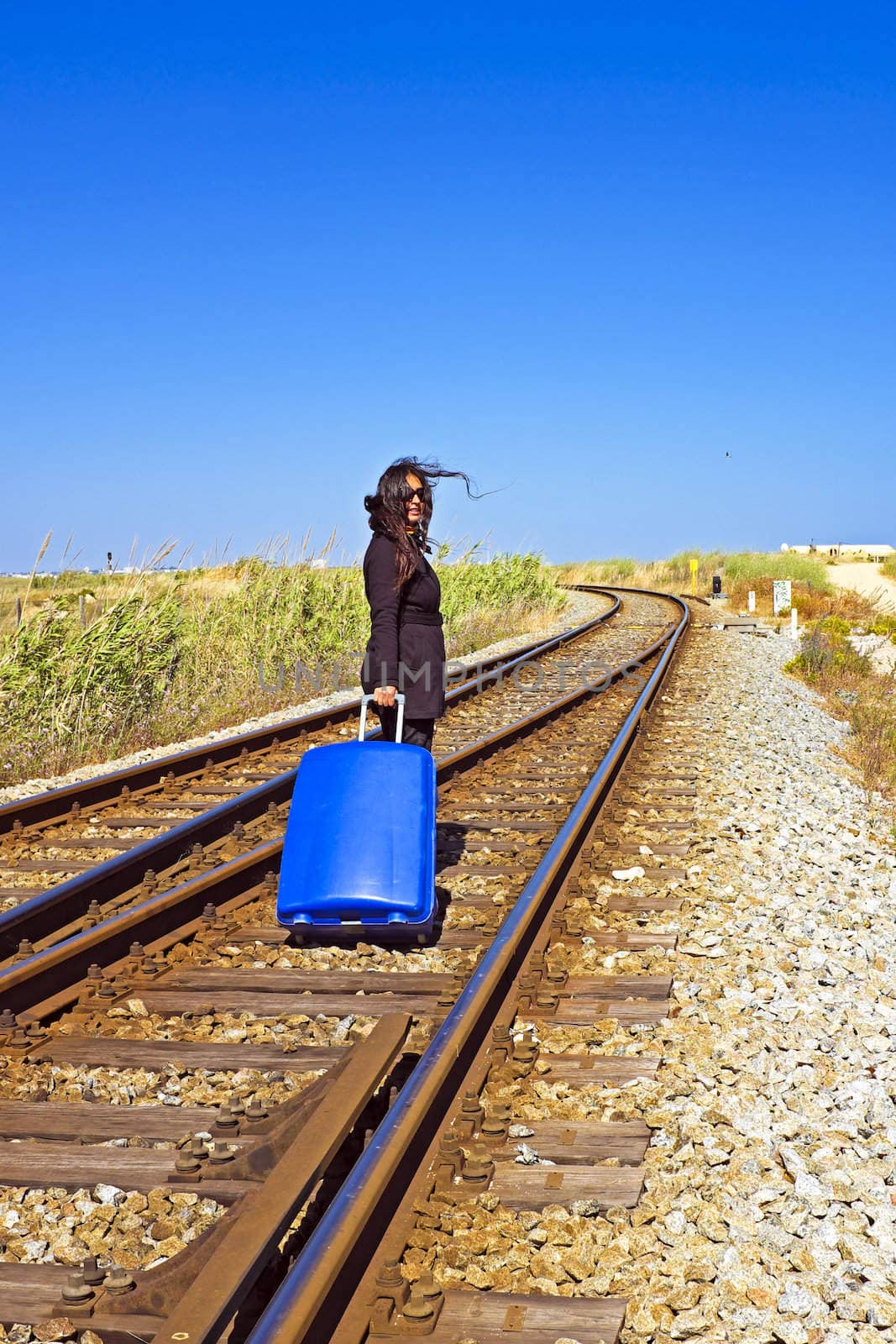 Young woman with her suitcase on a railroad track