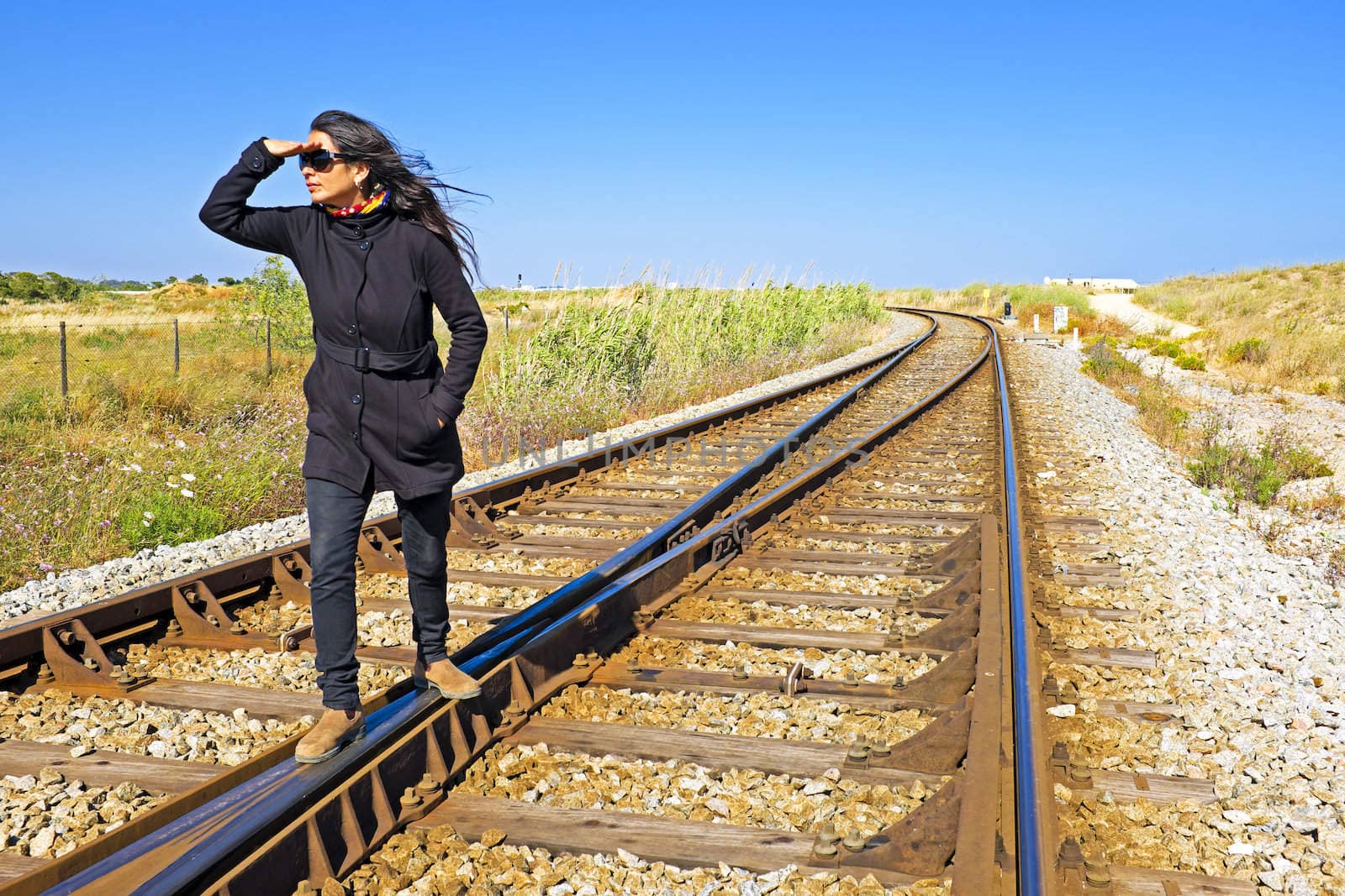 Young woman with her suitcase waiting at a railroad track