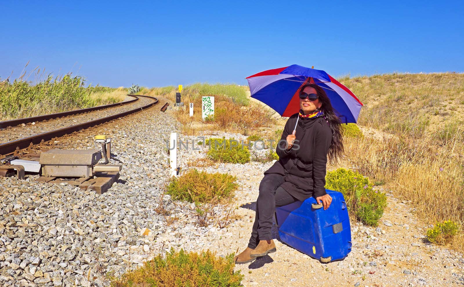 Young woman with her suitcase waiting at a railroad track by devy