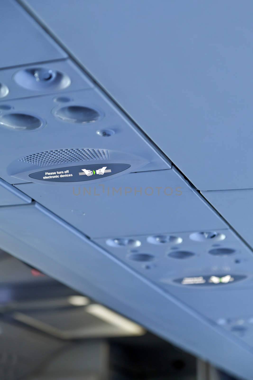 vertical color portrait captured in a passenger airline somewhere in europe shot passenger cabin ceiling and advisory lights for fasten seat belts and switch off electronic equipment and devices such as mobile phones