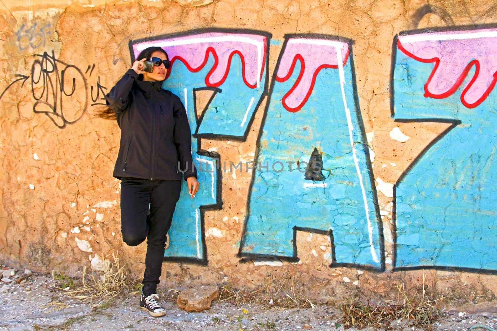 Smoking woman phoning at a graffiti wall by devy