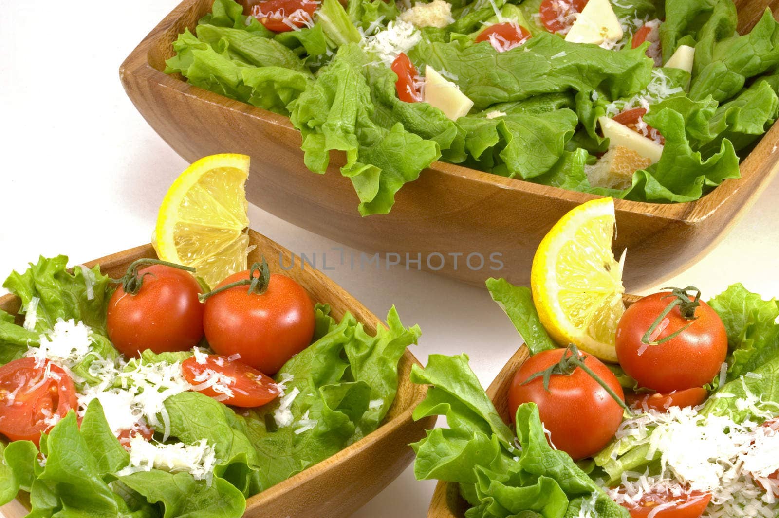A free salad of lettuce, tomatoes, and cheese in wooden bowls.