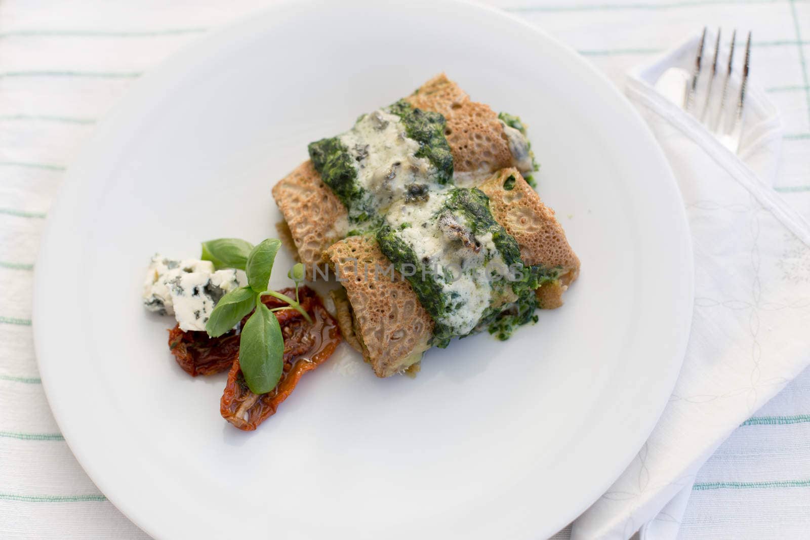 Tasty salty pancakes with spinach, roquefort, dried tomatoes and basil.