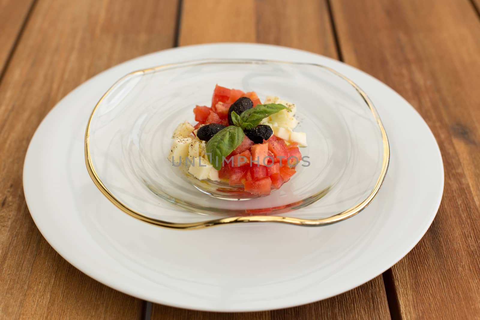 Delicious mozzarella, tomato tartar in soup glass plate on a wooden table.