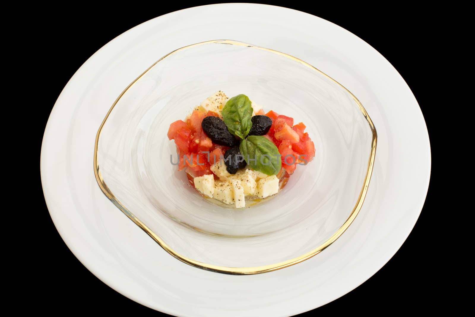Delicious tomatoes, mozzarella tartar in glass plate on a black background.