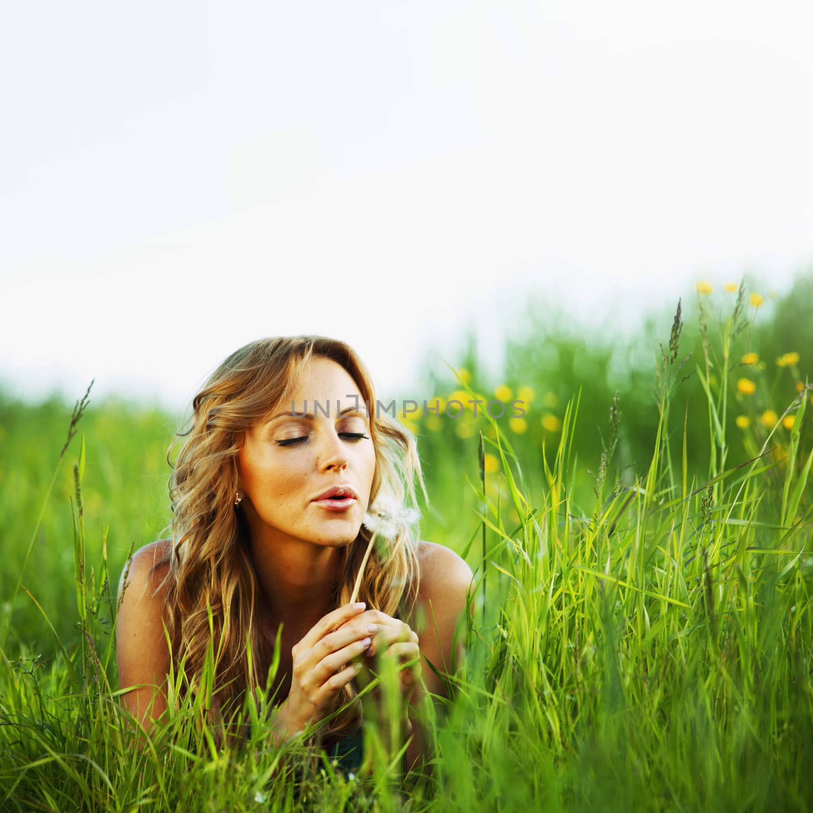 girl blow on dandelion on green field