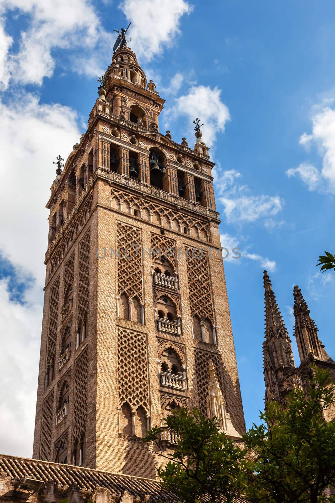 Giralda Spire, Bell Tower, Giraldillo Statue, Seville Cathedral, Cathedral of Saint Mary of the See, Seville, Andalusia Spain.  Giralda was built in 1184 as a minaret and in 1500s converted to a bell tower.   Largest Gothic Cathedral in the World and Third Largest Church in the World.  Burial Place of Christopher Columbus. 