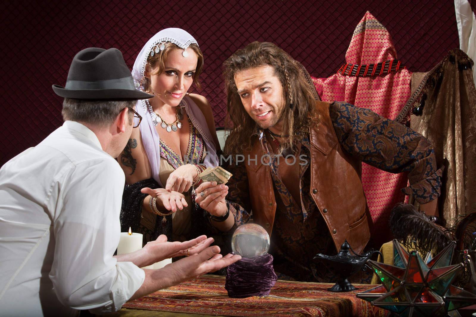 Helpless customer with fortune teller holding his money