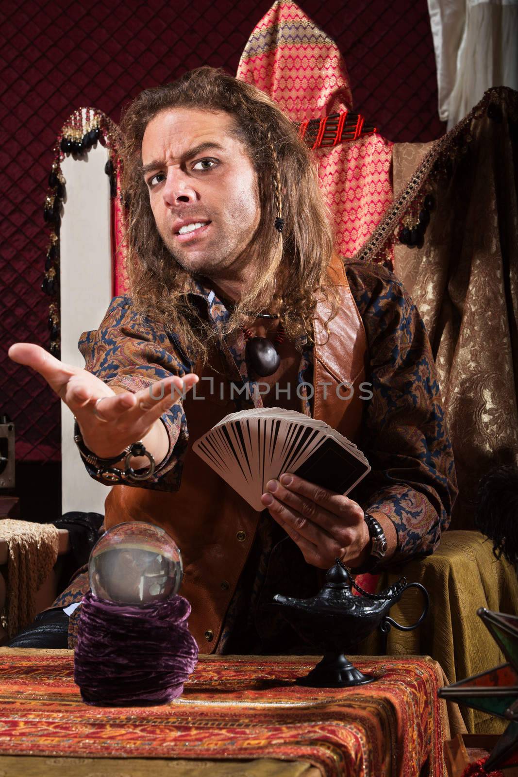 Handsome male fortune teller with tarot cards and crystal ball