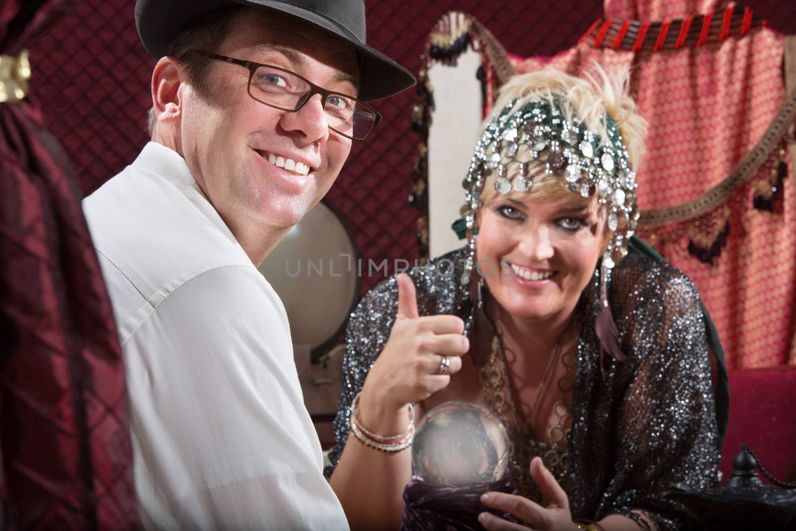 Happy fortune teller and customer with glowing crystal ball