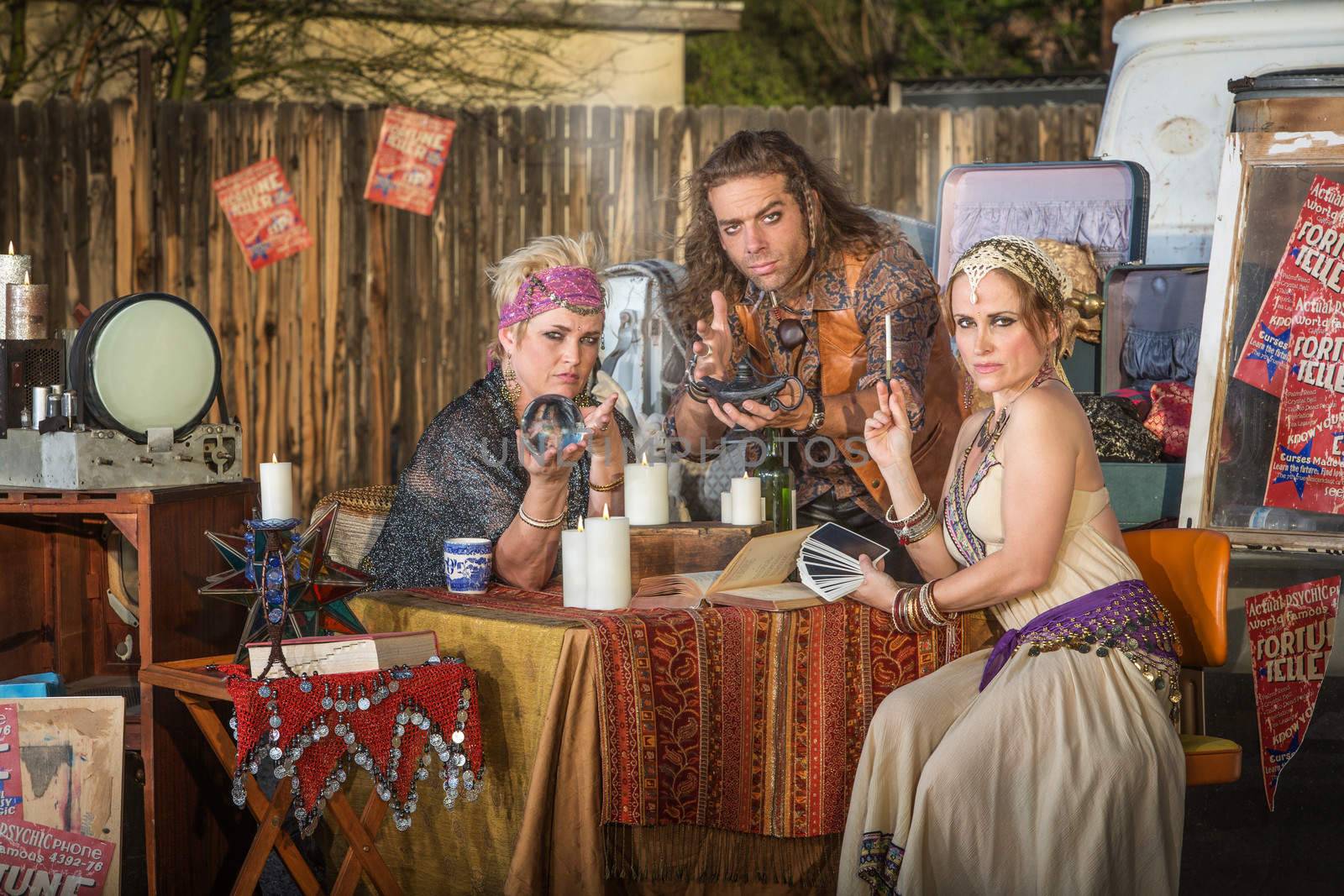 Three serious gypsy fortune tellers with outdoor kiosk