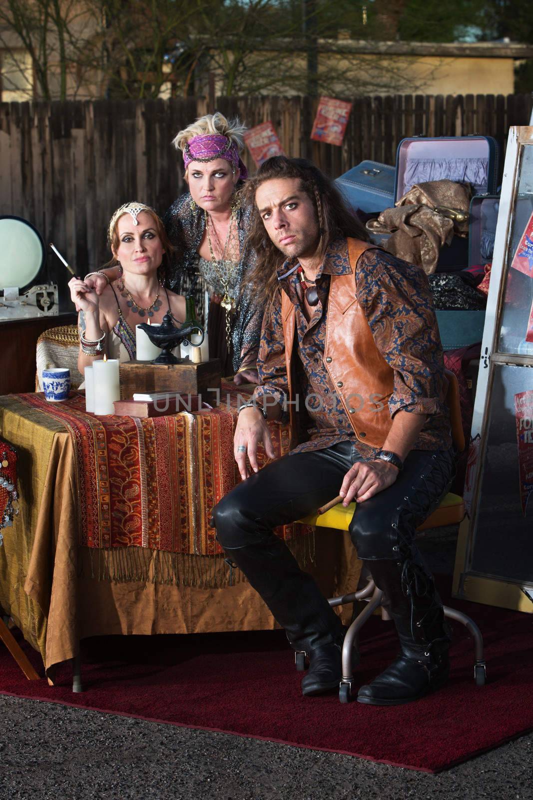 Handsome gypsy man sitting with female fortune tellers