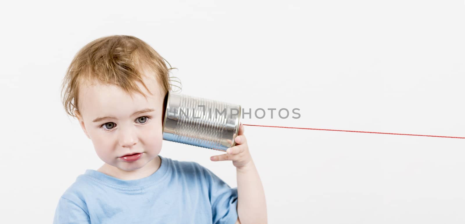 young, disappointed child listening to tin can phone. caucasian child in horizontal image