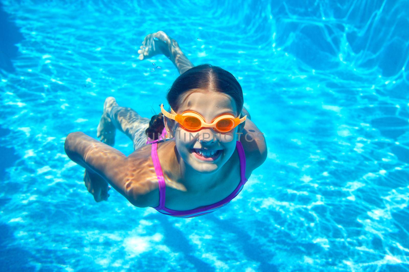 The little girl in the water park swimming underwater and smiling