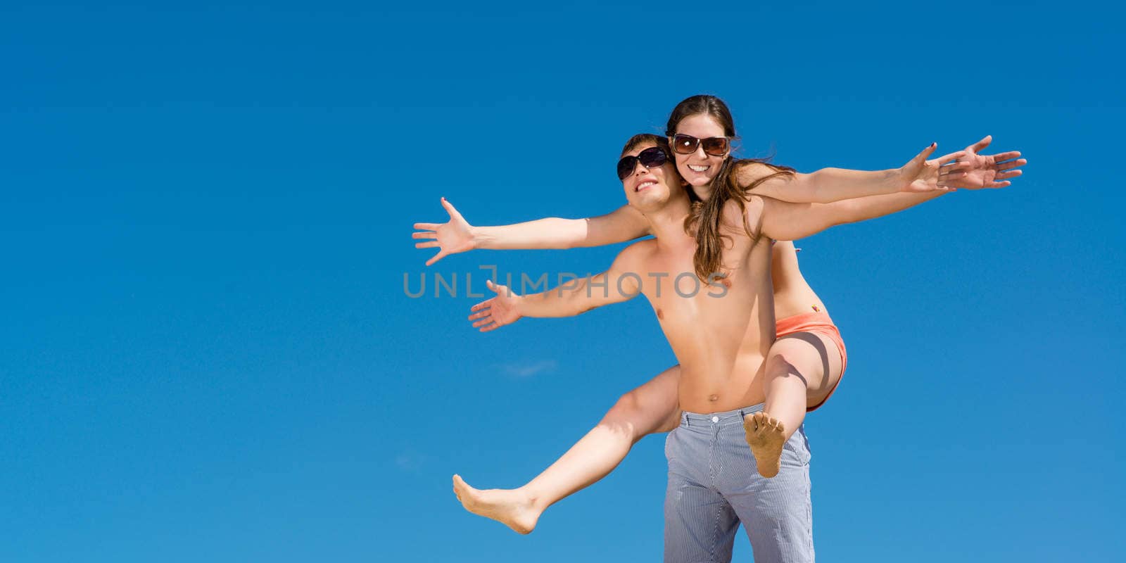 Young couple hugging on a background of blue sky, hold together honeymoon
