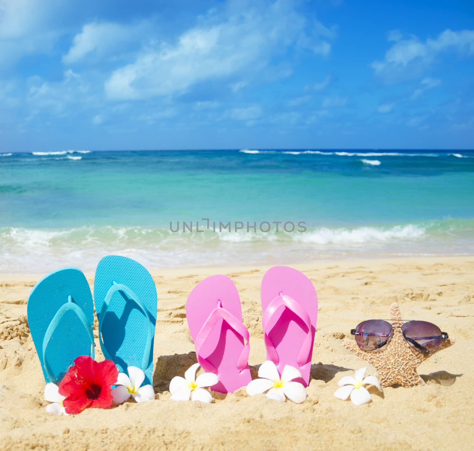 Flip flops and starfish with sunglasses with tropical flowers on sandy beach in Hawaii, Kauai