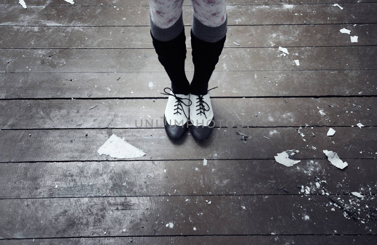 Human legs in stylish shoes standing on the old dirty wooden floor