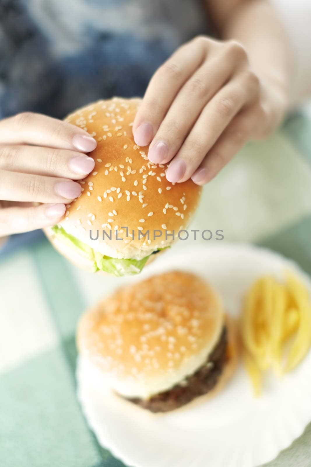 Woman holding humburger and sitting at the table